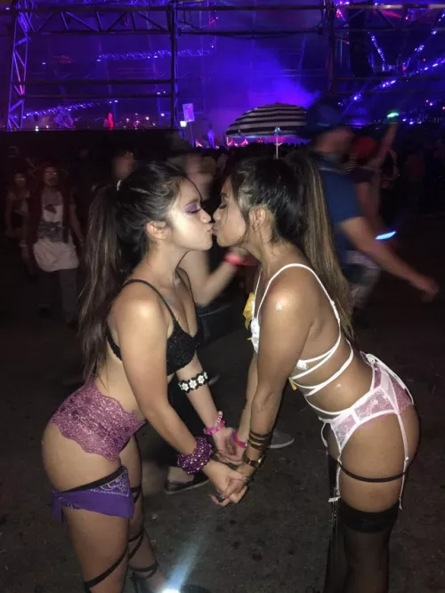 Two beautiful girls kissing at a music festival by brassuka